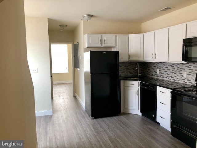 kitchen with wood-type flooring, black appliances, white cabinetry, and backsplash