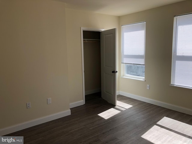 unfurnished bedroom featuring a closet and dark wood-type flooring