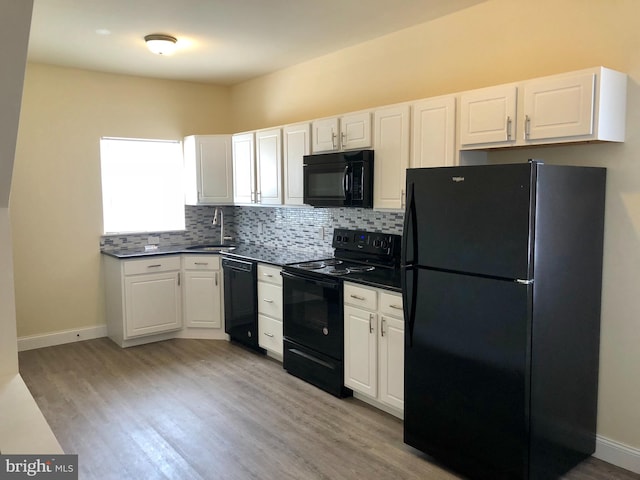 kitchen featuring white cabinets, backsplash, black appliances, light hardwood / wood-style flooring, and sink