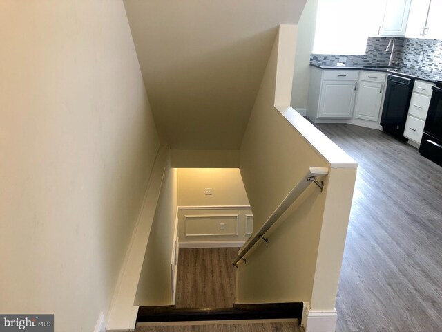 stairs featuring hardwood / wood-style floors and sink