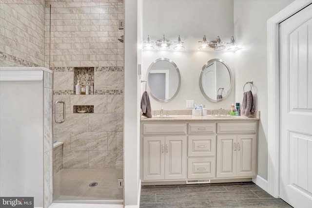 bathroom featuring a shower with door and vanity