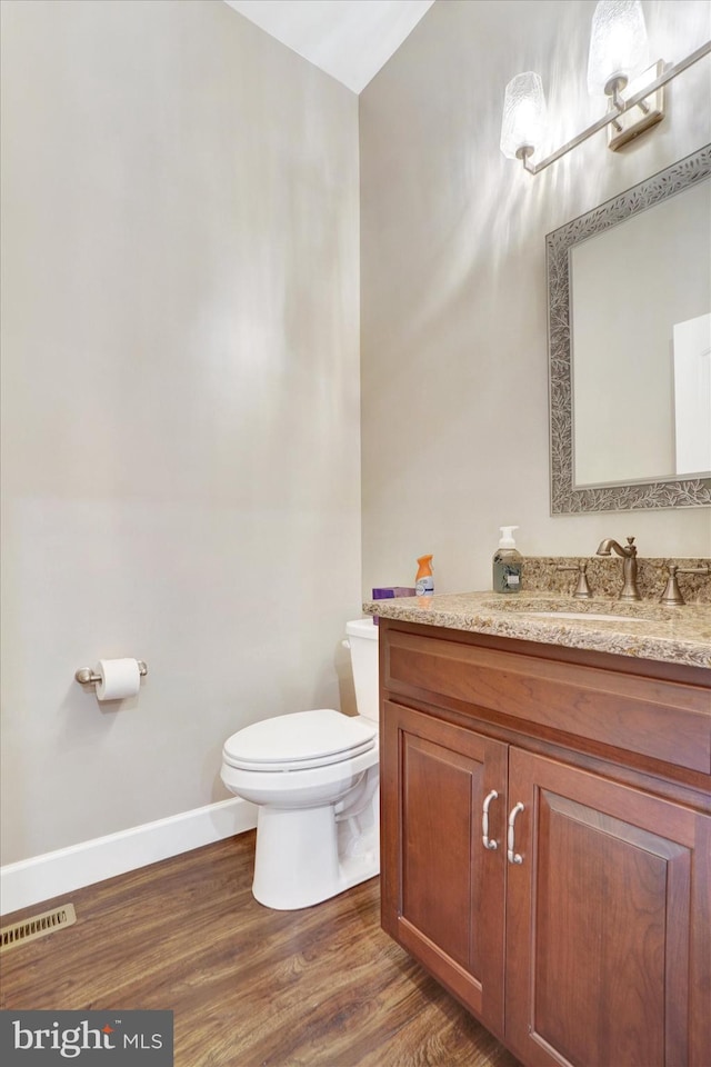 bathroom with vanity, toilet, and hardwood / wood-style flooring