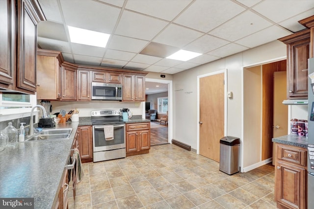 kitchen with light tile patterned floors, appliances with stainless steel finishes, a drop ceiling, and sink