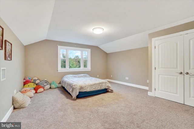 carpeted bedroom with lofted ceiling and a closet