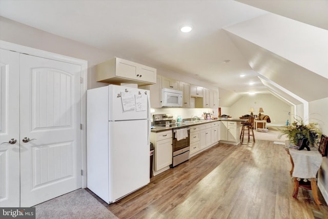 kitchen featuring sink, white cabinets, vaulted ceiling, light hardwood / wood-style flooring, and white appliances