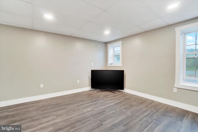 unfurnished room with hardwood / wood-style flooring, a drop ceiling, and a healthy amount of sunlight