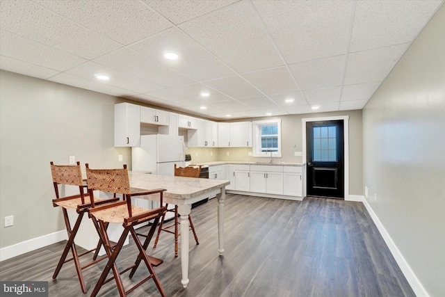 kitchen with white refrigerator, black electric range, a paneled ceiling, dark wood-type flooring, and white cabinetry