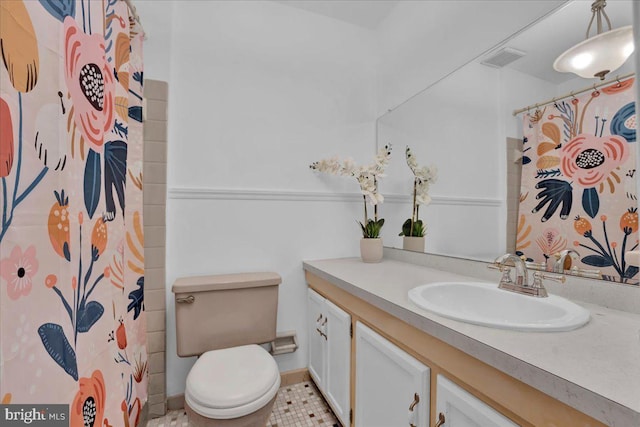 bathroom featuring walk in shower, vanity, toilet, and tile patterned floors