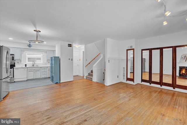 unfurnished living room with light hardwood / wood-style floors and sink