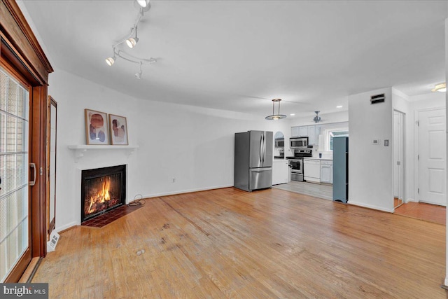 unfurnished living room featuring light hardwood / wood-style flooring and rail lighting