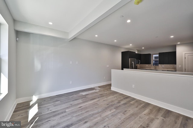 unfurnished living room with beamed ceiling and hardwood / wood-style flooring