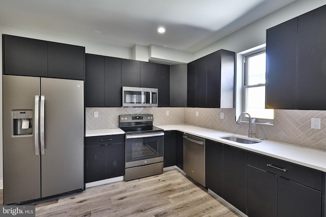 kitchen with light hardwood / wood-style flooring, backsplash, appliances with stainless steel finishes, and sink