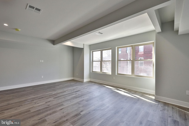 spare room featuring hardwood / wood-style flooring and beam ceiling