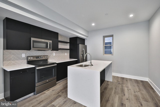 kitchen with a center island with sink, sink, light hardwood / wood-style flooring, and stainless steel appliances