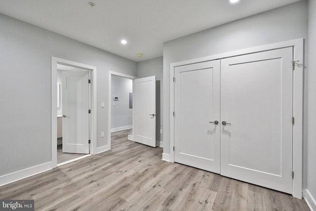 unfurnished bedroom with light wood-type flooring and a closet