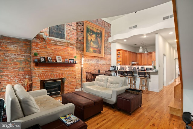 living room with light wood-type flooring, brick wall, and a fireplace