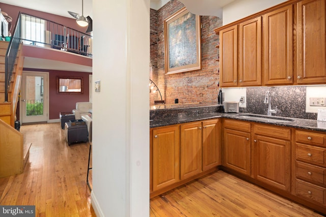 kitchen featuring dark stone countertops, light hardwood / wood-style floors, sink, and tasteful backsplash