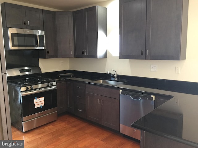 kitchen with dark brown cabinets, appliances with stainless steel finishes, dark hardwood / wood-style floors, and sink