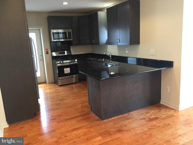 606 N 2nd St, Philadelphia, PA 19123 - kitchen featuring a peninsula, dark countertops, appliances with stainless steel finishes, light wood finished floors, and a sink