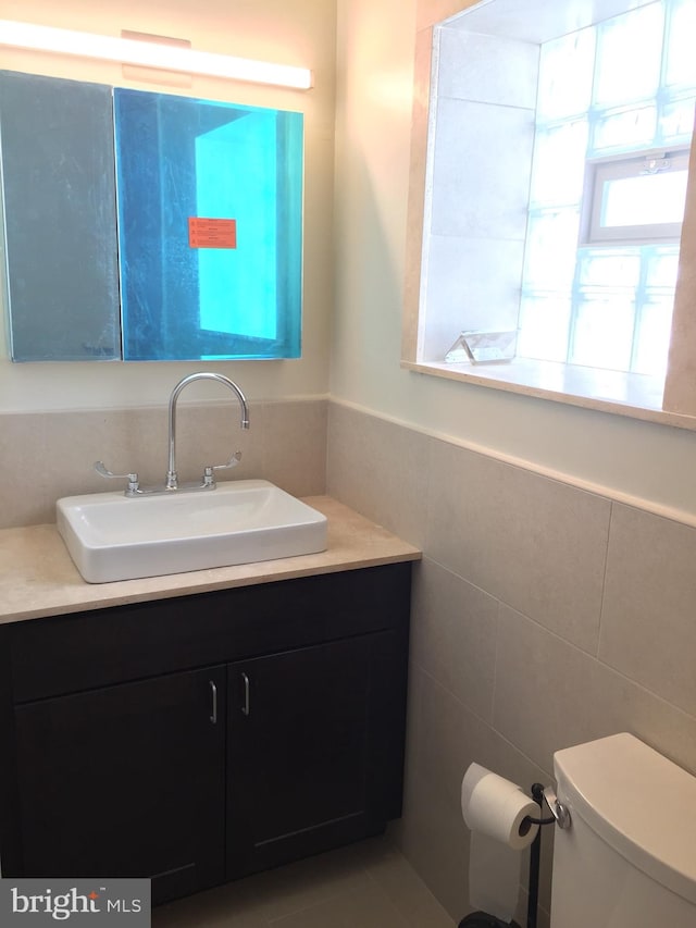 bathroom featuring tile walls, vanity, and toilet