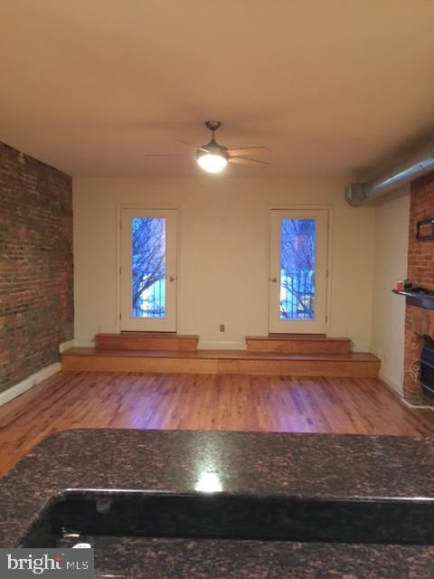 606 N 2nd St, Philadelphia, PA 19123 - unfurnished living room with brick wall, a fireplace, wood finished floors, and ceiling fan
