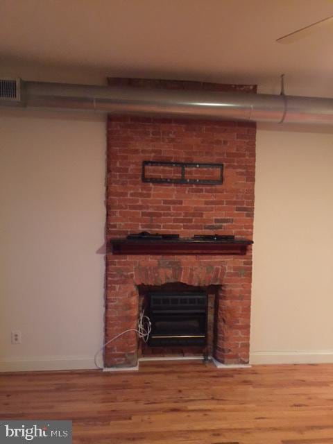 details with a brick fireplace and hardwood / wood-style flooring