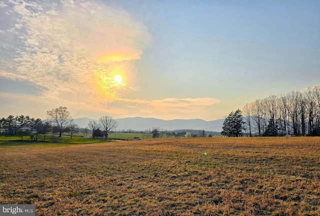 yard at dusk featuring a mountain view and a rural view