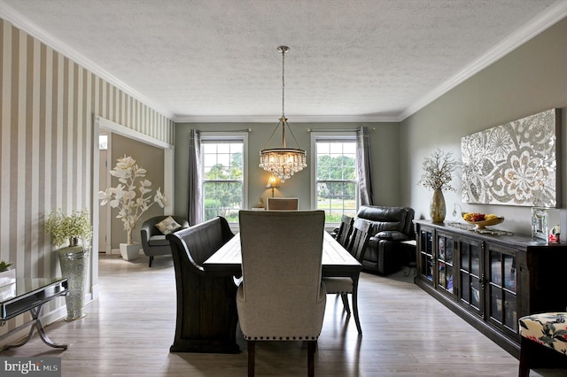 dining space with crown molding, light hardwood / wood-style flooring, a notable chandelier, and a textured ceiling