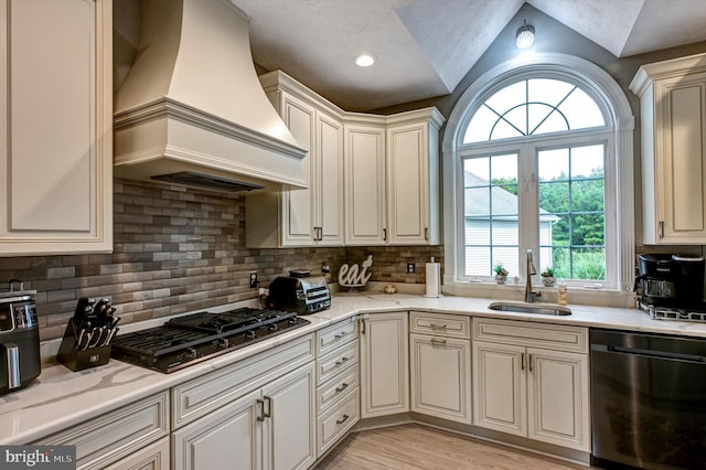 kitchen featuring gas stovetop, dishwasher, custom range hood, sink, and vaulted ceiling