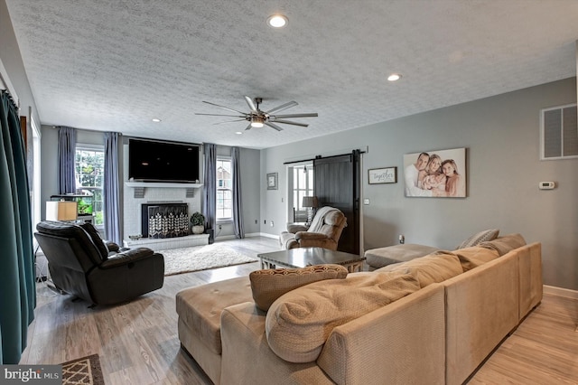 living room featuring light hardwood / wood-style floors, a healthy amount of sunlight, a textured ceiling, and a barn door