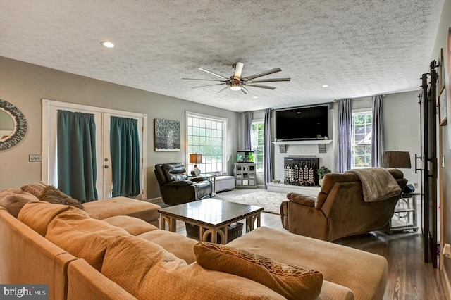 living room featuring ceiling fan, hardwood / wood-style flooring, a textured ceiling, and plenty of natural light