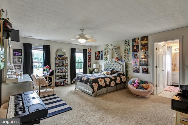 bedroom with connected bathroom, a textured ceiling, light colored carpet, and ceiling fan