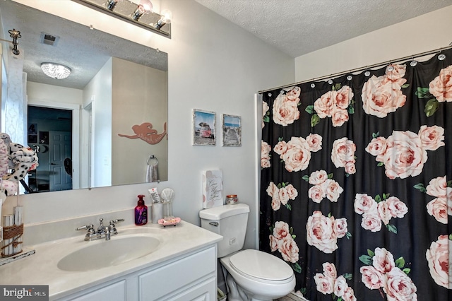 bathroom with vanity, toilet, a textured ceiling, and walk in shower