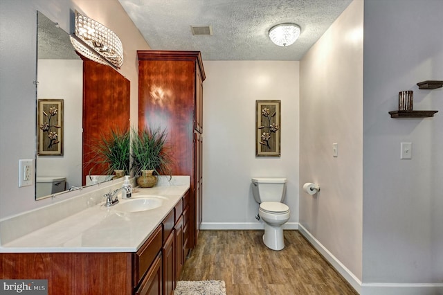 bathroom with toilet, a textured ceiling, vanity, and wood-type flooring