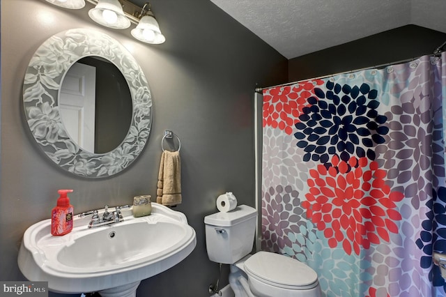 bathroom with toilet, a textured ceiling, sink, and a shower with shower curtain