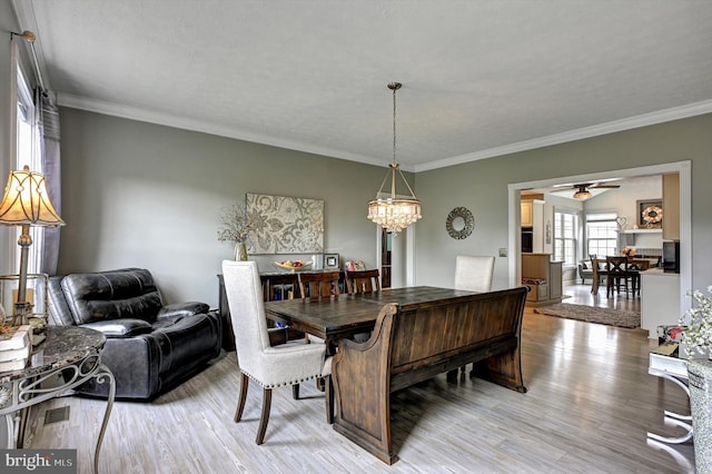 dining room with light hardwood / wood-style floors, crown molding, a textured ceiling, and ceiling fan with notable chandelier