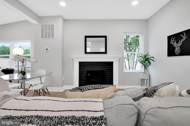 living room with wood-type flooring, a fireplace, plenty of natural light, and lofted ceiling with beams