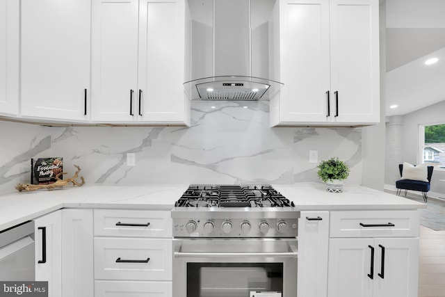 kitchen with light stone counters, white cabinets, wall chimney exhaust hood, backsplash, and appliances with stainless steel finishes