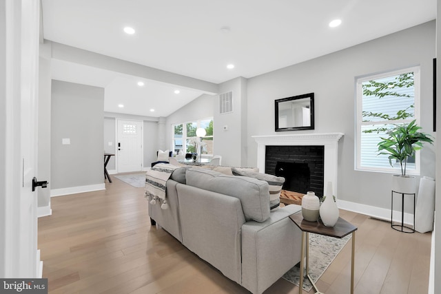 living room with lofted ceiling, light hardwood / wood-style floors, and a fireplace