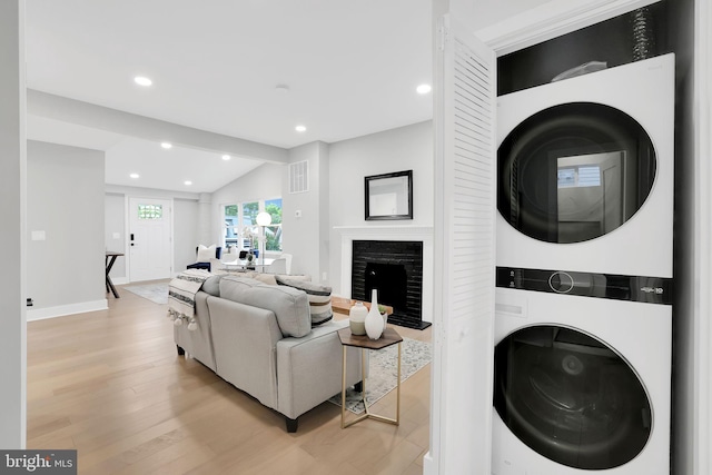 clothes washing area featuring light hardwood / wood-style flooring and stacked washing maching and dryer