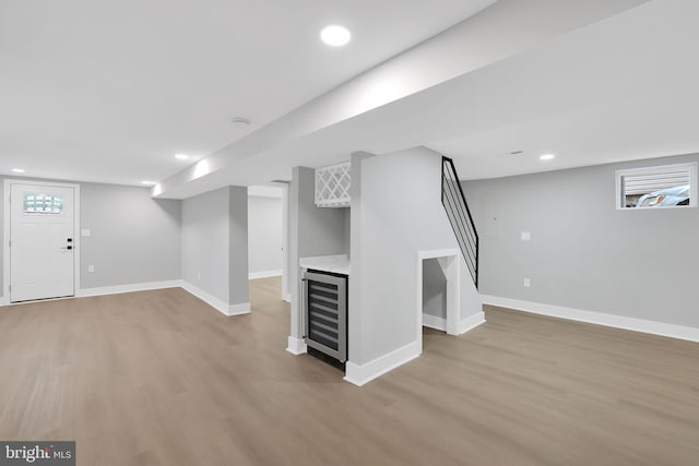 basement with wine cooler and light hardwood / wood-style flooring