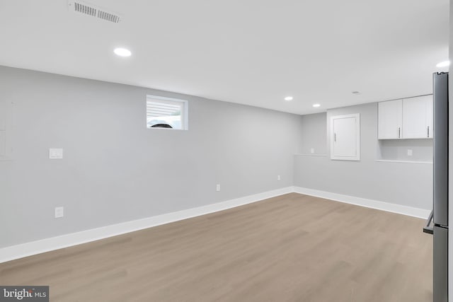 basement featuring stainless steel refrigerator and light hardwood / wood-style floors