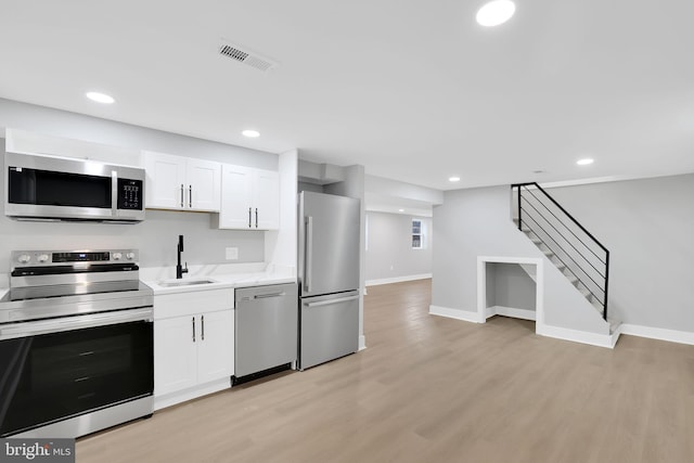 kitchen with white cabinets, stainless steel appliances, light wood-type flooring, and sink