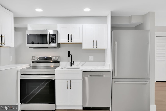 kitchen featuring light stone counters, sink, white cabinetry, stainless steel appliances, and light wood-type flooring