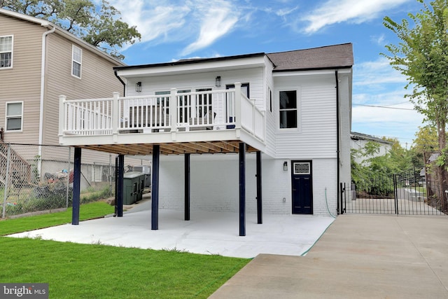 back of property with a lawn, a patio, and a wooden deck