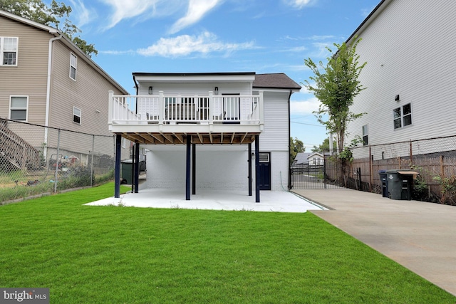 rear view of property featuring a wooden deck, a yard, and a patio