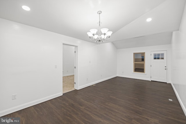 spare room with dark hardwood / wood-style floors, an inviting chandelier, and vaulted ceiling