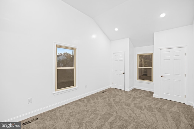 carpeted spare room with lofted ceiling