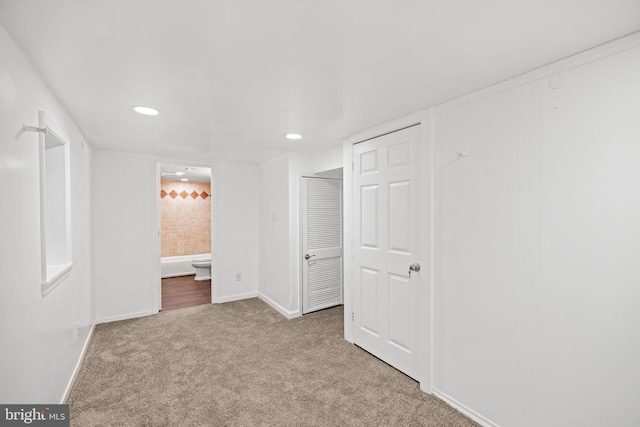 unfurnished bedroom featuring light colored carpet and ensuite bath