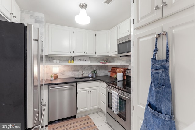 kitchen featuring tasteful backsplash, sink, white cabinetry, stainless steel appliances, and light tile patterned floors